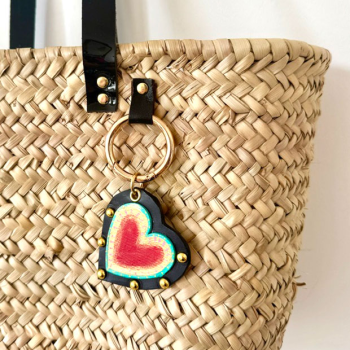 Detail of a layered black and red leather heart charm, hand-painted and finished with metal rivets