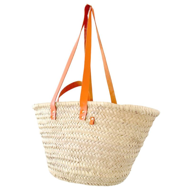 Detail of orange upcycled leather handles attached to a handwoven palm leaf straw basket