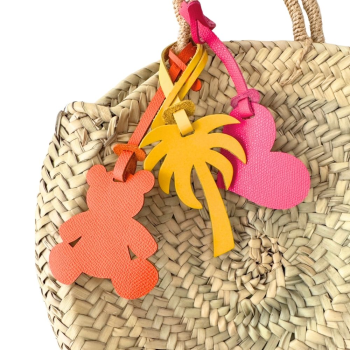 Upcycled leather heart bag charm attached to a straw beach basket