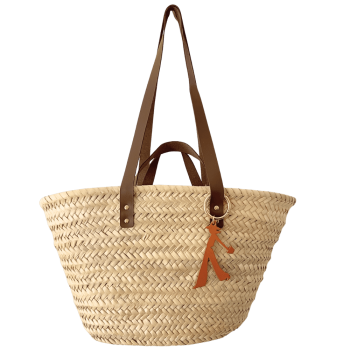 Bijou de sac en cuir camel accroché à un panier en paille