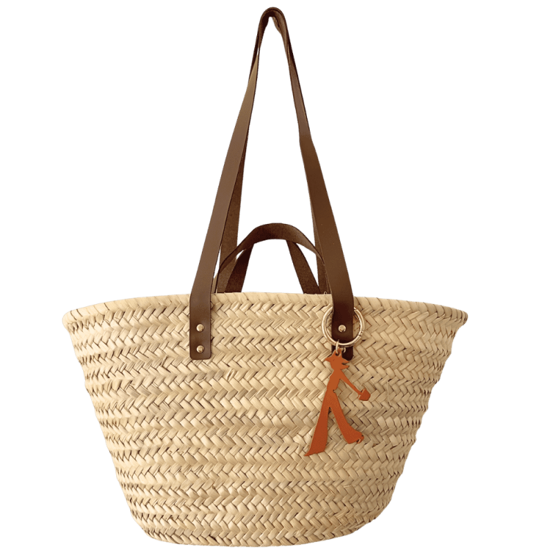 Bijou de sac en cuir camel accroché à un panier en paille